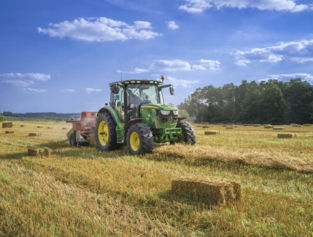 green tractor on brown grass field under blue sky during daytime